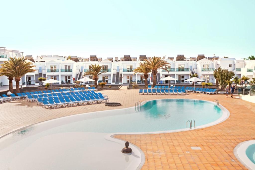una gran piscina en un complejo con sillas azules en Blue Sea Lanzarote Palm, en Puerto del Carmen