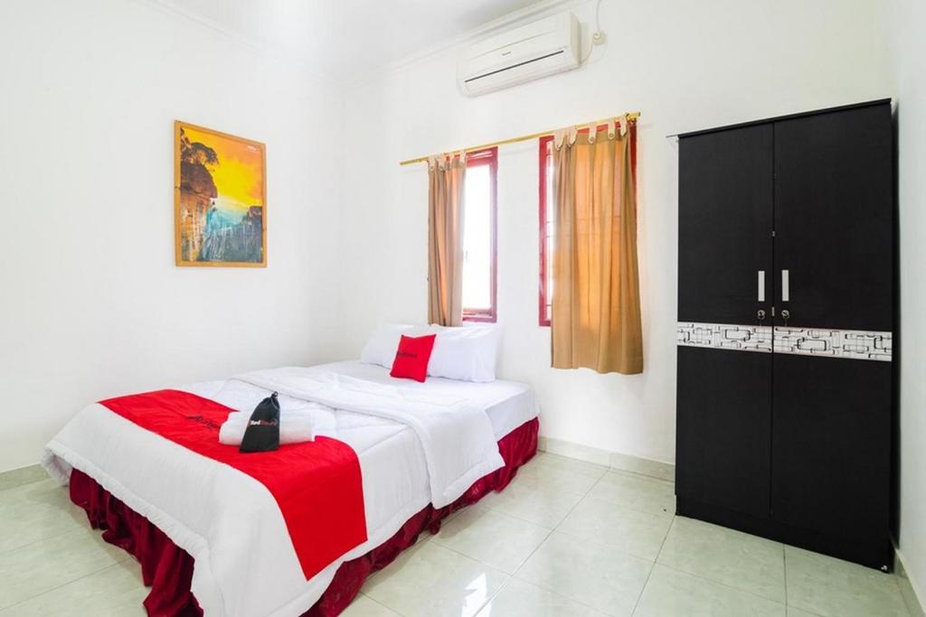 CimanggisにあるRedDoorz near Universitas Pamulangのベッドルーム1室(ベッド1台、赤と白の毛布付)