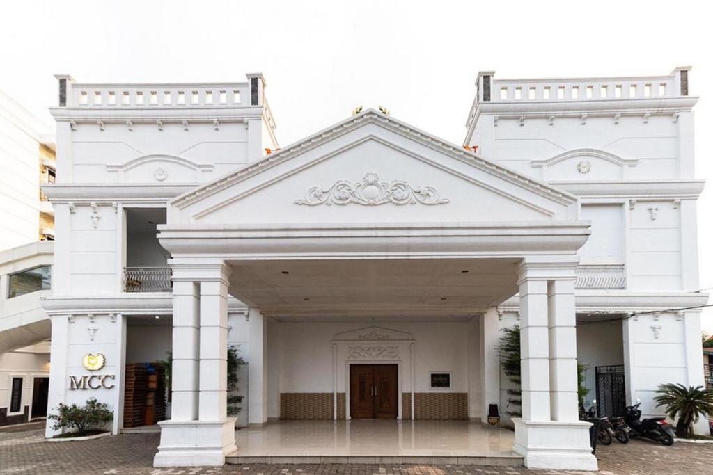 een wit neoklassiek gebouw met een grote ingang bij RedDoorz @ Binjai in Binjai