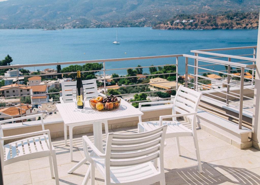 una mesa y sillas en un balcón con vistas al agua en Kalavria Luxury Suites - magnificent sea view of Poros, en Poros