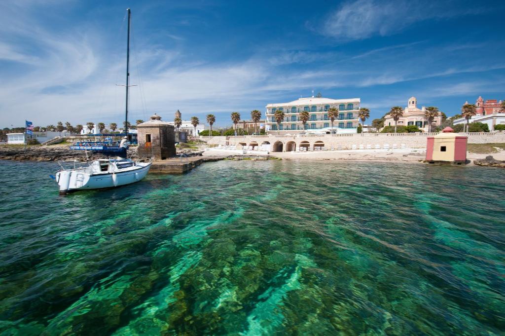 een boot in het water voor een gebouw bij Hotel Terminal - Caroli Hotels in Leuca