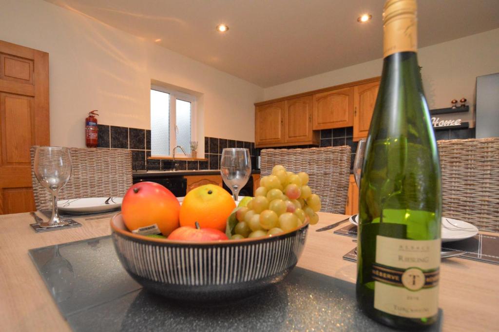 eine Flasche Wein und eine Schale Obst auf dem Tisch in der Unterkunft Bay Cottage in Dunoon