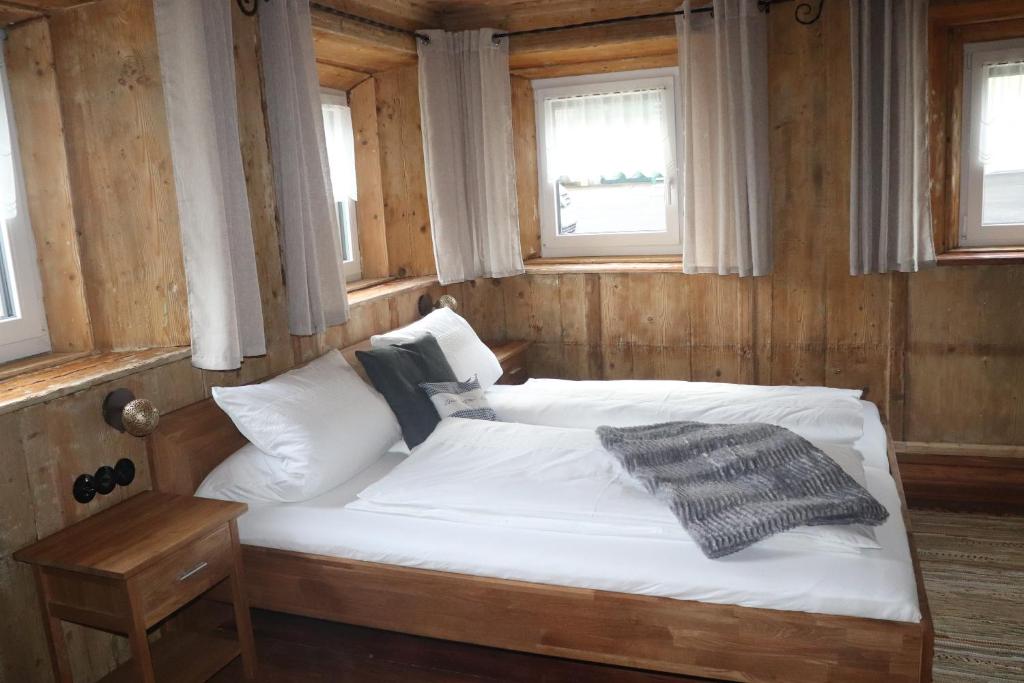 a bed in a room with wooden walls and windows at Haus Neuwirt in Sautens