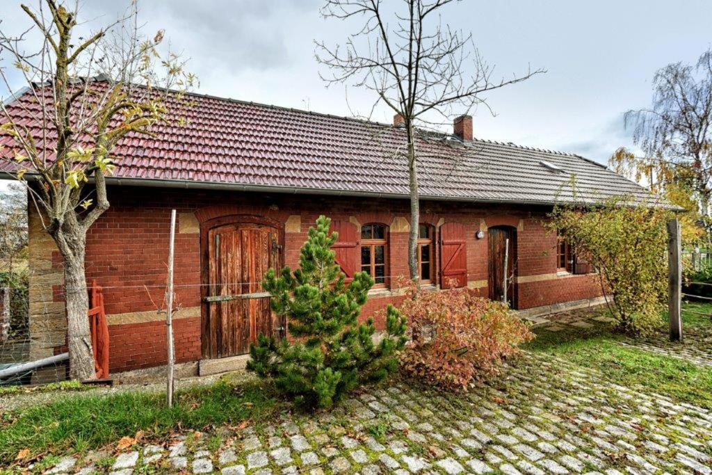 una casa de ladrillo rojo con un árbol delante en Ferienhaus "Alter Güterschuppen", en Naumburg