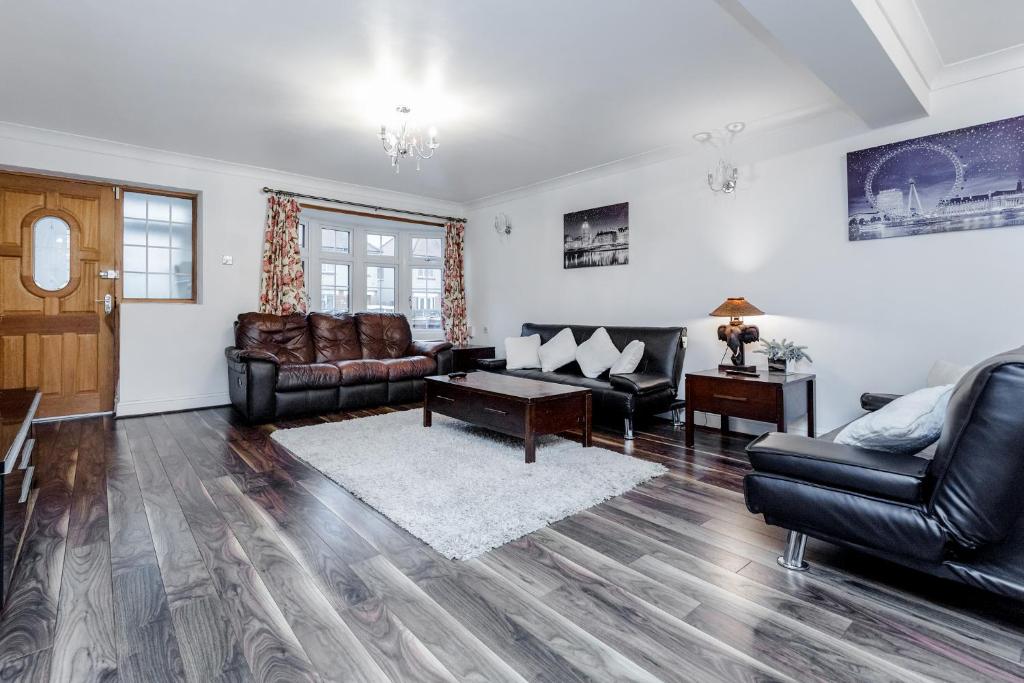 a living room with leather furniture and a table at LARGE MODERN HOME, FOUR BEDROOM, TWO BATHROOM in Grays Thurrock