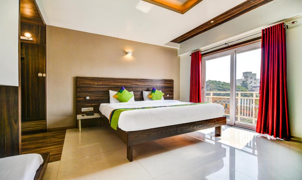 a bedroom with a bed and a large window at Treebo Trend Shree Sai Suites in Kolhapur
