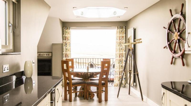 a kitchen with a table and chairs and a window at Seagull's Sanctuary in Wells next the Sea