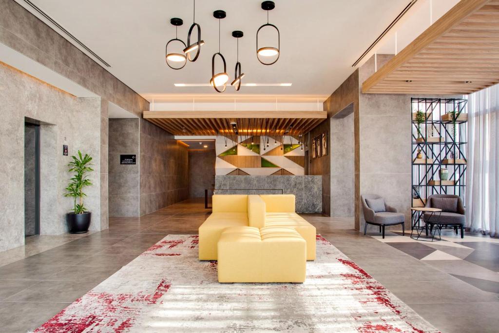 a living room with a yellow couch and a rug at Lemon Tree Hotel, Jumeirah Dubai in Dubai