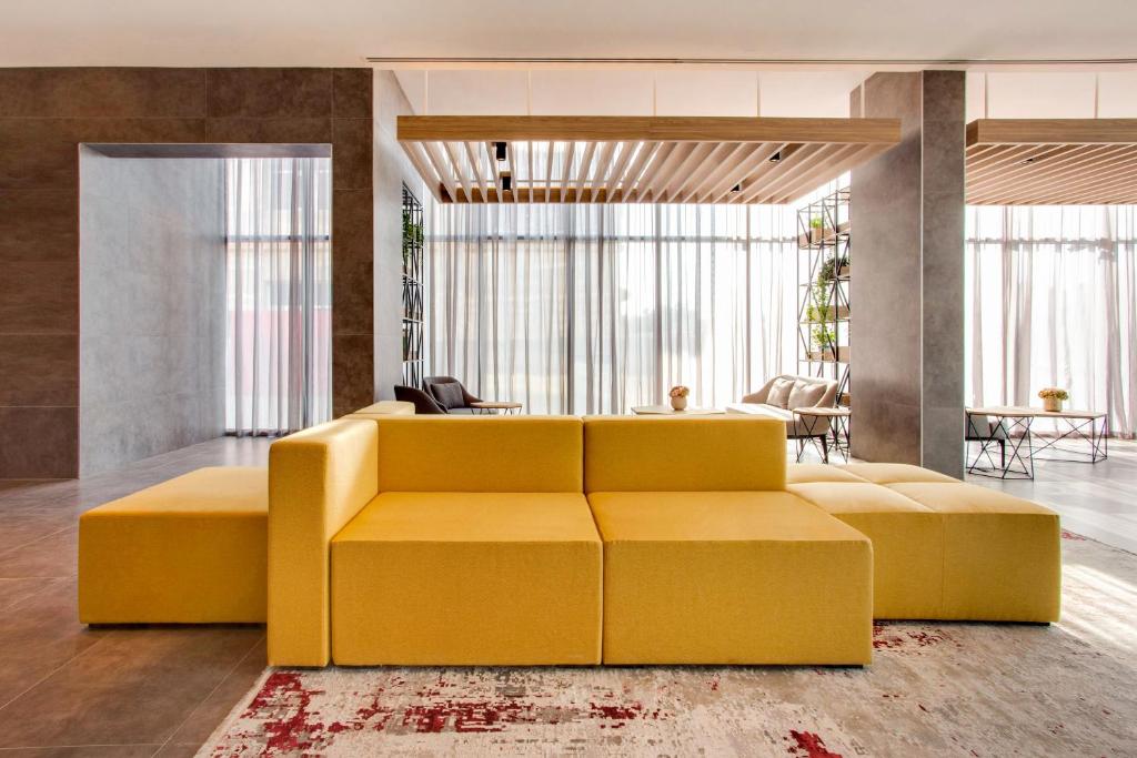 a living room with a yellow couch and a table at Lemon Tree Hotel, Jumeirah Dubai in Dubai