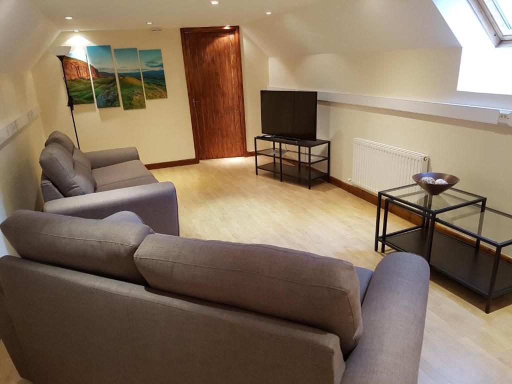 a living room with a couch and a tv at The Loft Apartment in Abergavenny