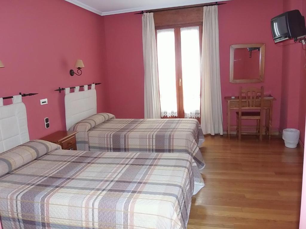 2 camas en una habitación de hotel con paredes rosas en Hostal-Restaurante San Antolín, en Tordesillas