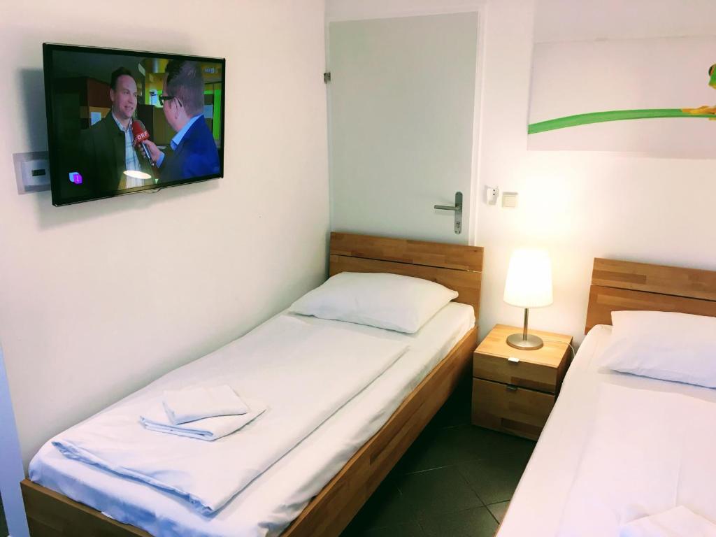 dwa łóżka w pokoju z telewizorem na ścianie w obiekcie AJO Apartments - Alte Donau Terrace Studio - Self-Check-in w Wiedniu