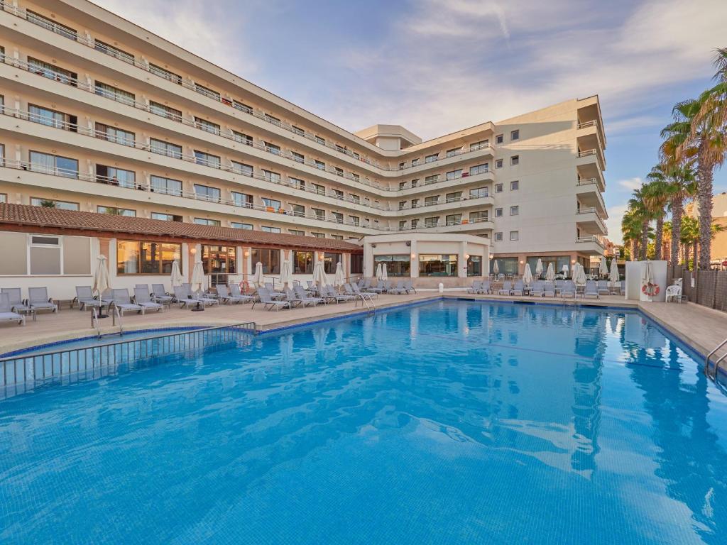 una piscina de hotel con sillas y un hotel en BQ Can Picafort Hotel, en Can Picafort