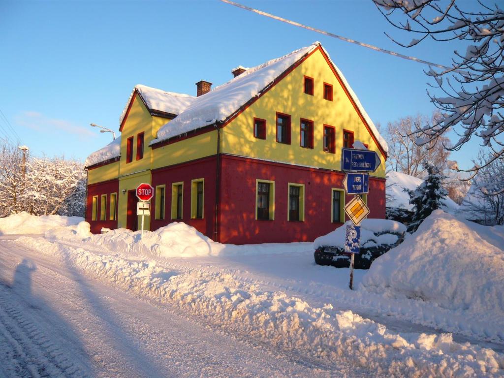 a red and yellow house is covered in snow at Apartmány Liška in Mladé Buky