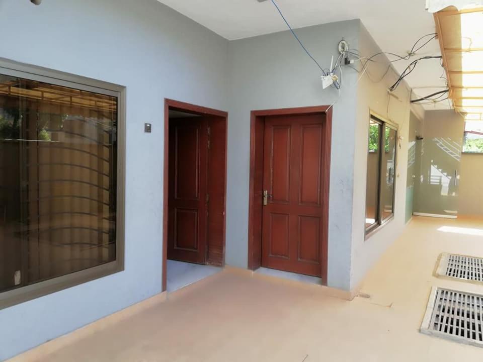 two brown doors on a white wall with windows at AB Guesthouse in Rawalpindi