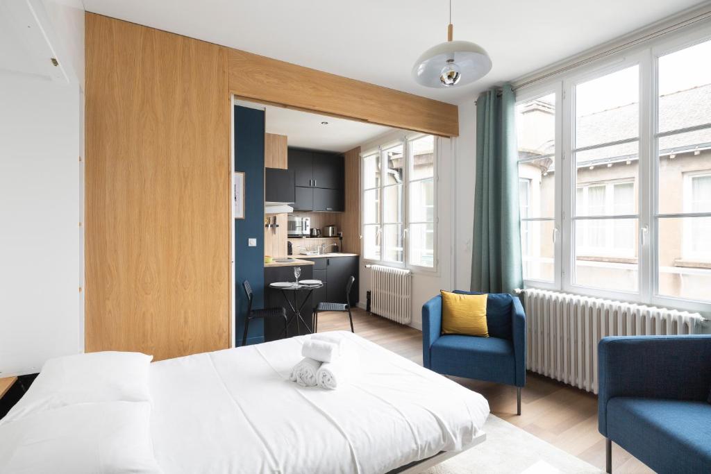Cet appartement comprend une chambre avec un lit et deux chaises ainsi qu'une cuisine. dans l'établissement Le Cinq by Cocoonr, à Nantes