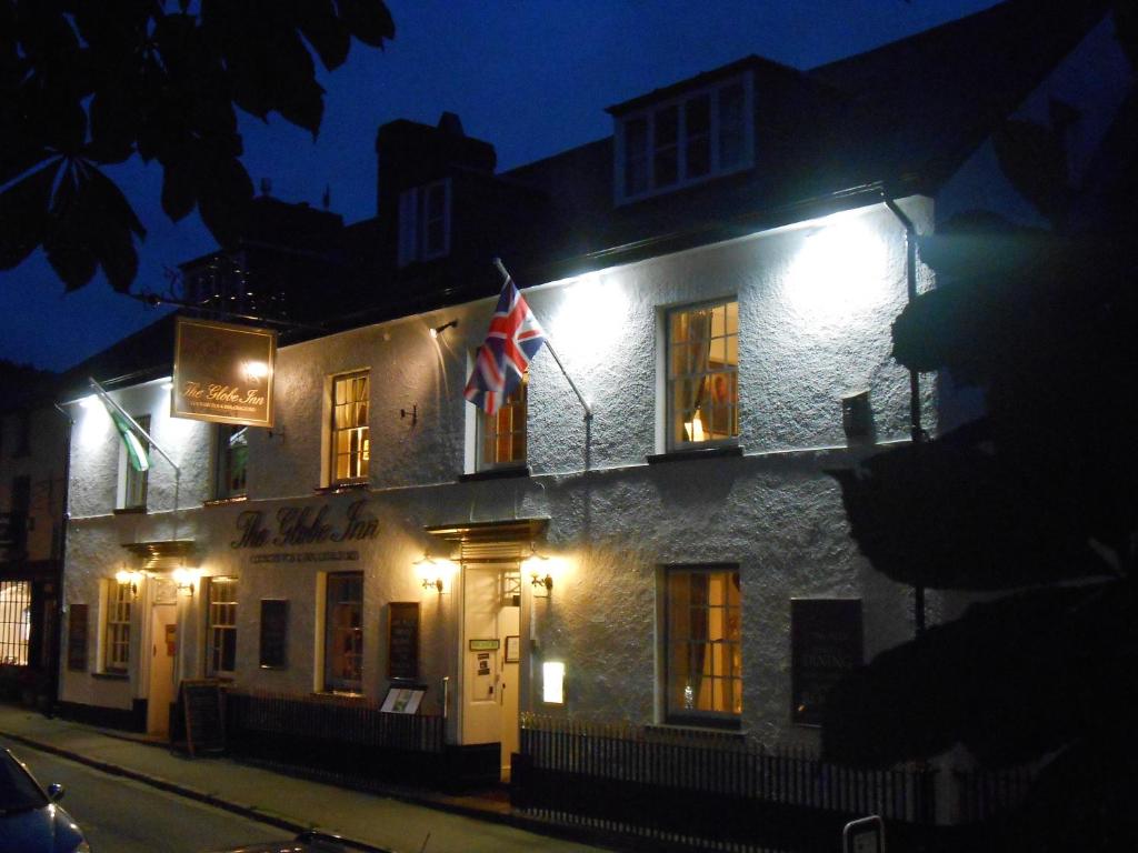 un edificio con una bandera a un lado por la noche en The Globe Inn en Chagford