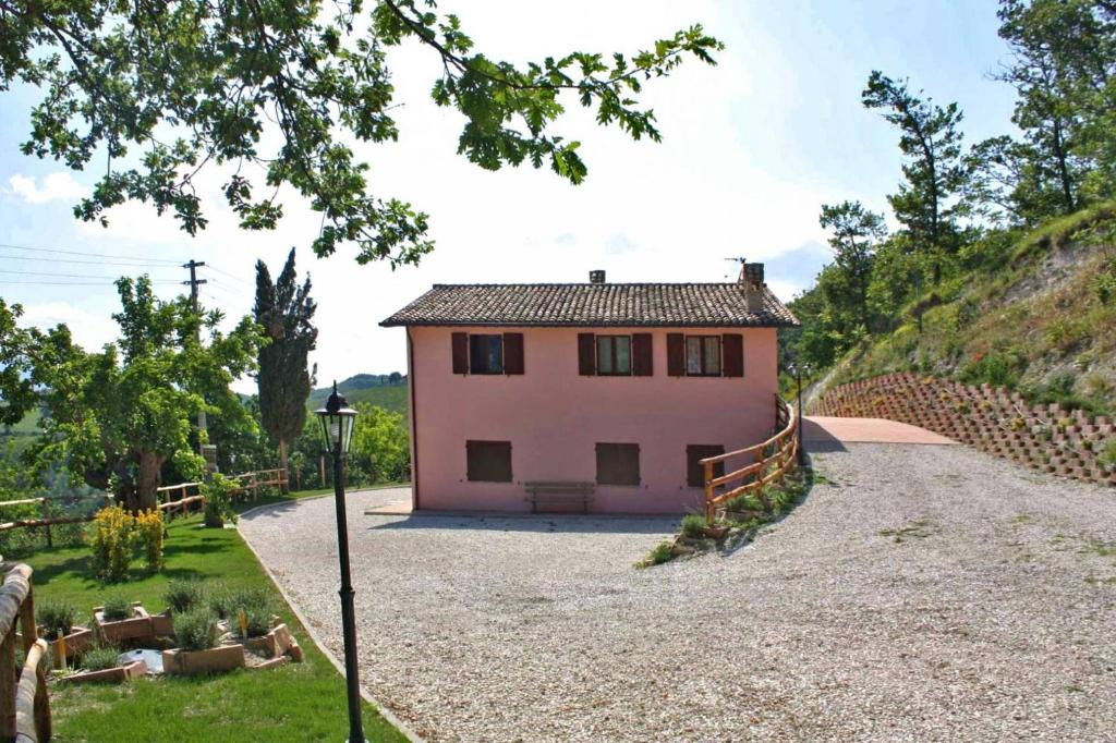 a small pink house sitting on top of a hill at Casale La Veduta in Acqualagna