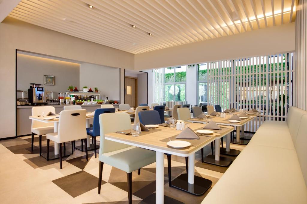 a dining room with tables and chairs and windows at Lemon Tree Hotel, Jumeirah Dubai in Dubai