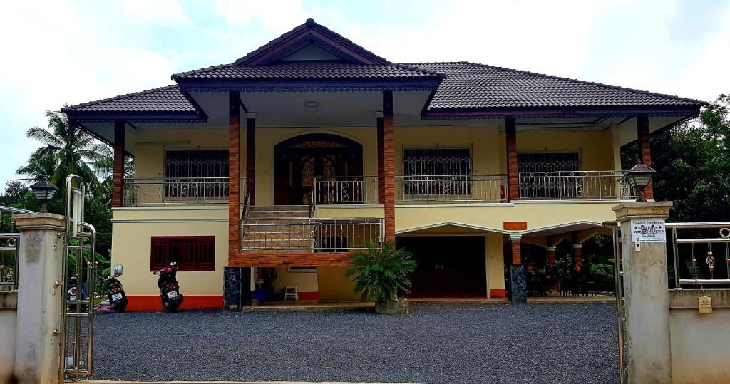 una casa con balcón y una motocicleta aparcada delante en Khwahol Guesthouse, en Don Sak