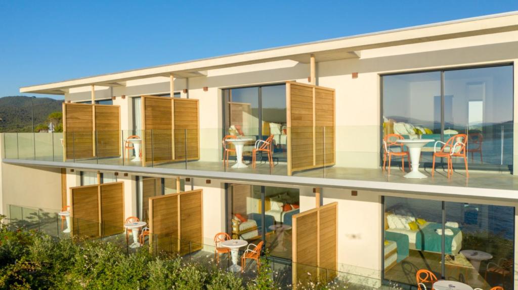 an apartment building with balconies with tables and chairs at Hotel le Jardin d'Emile in Porticcio