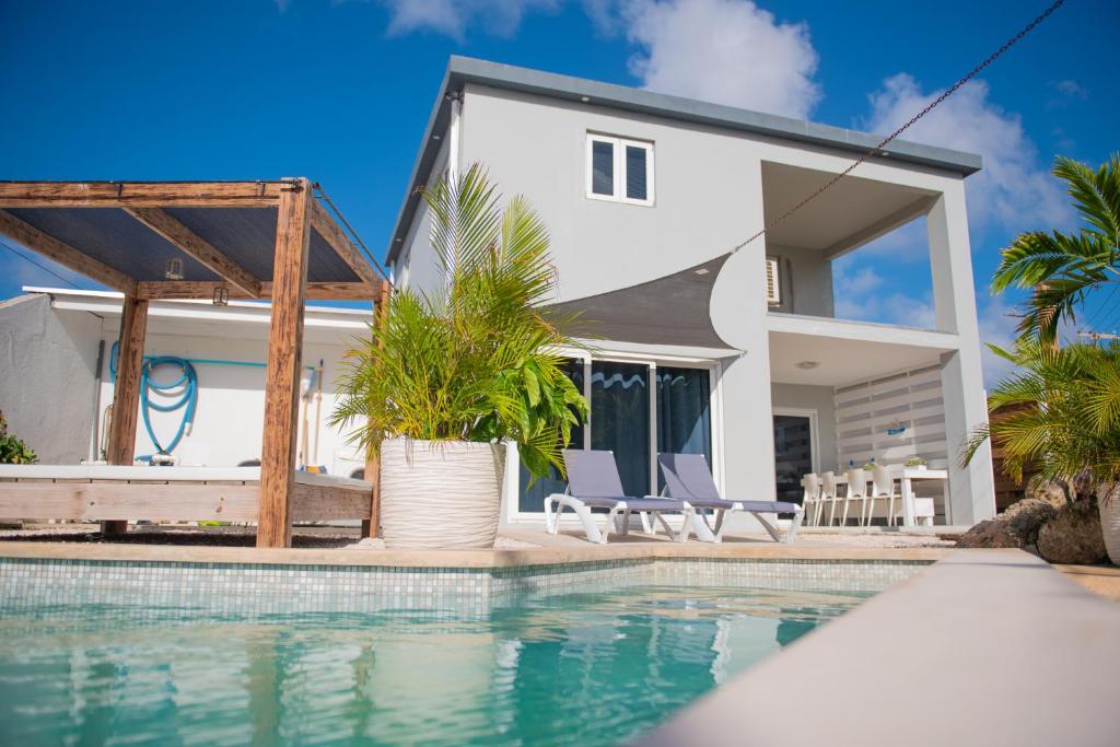 a villa with a swimming pool in front of a house at Sunny Hill Apartment in Willemstad