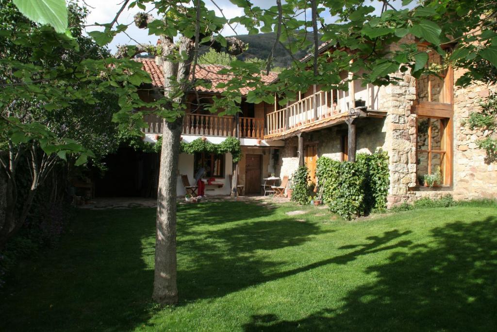 una vista exterior de una casa con un árbol en el patio en El Canto del Gallo en Ranedo de Curueño