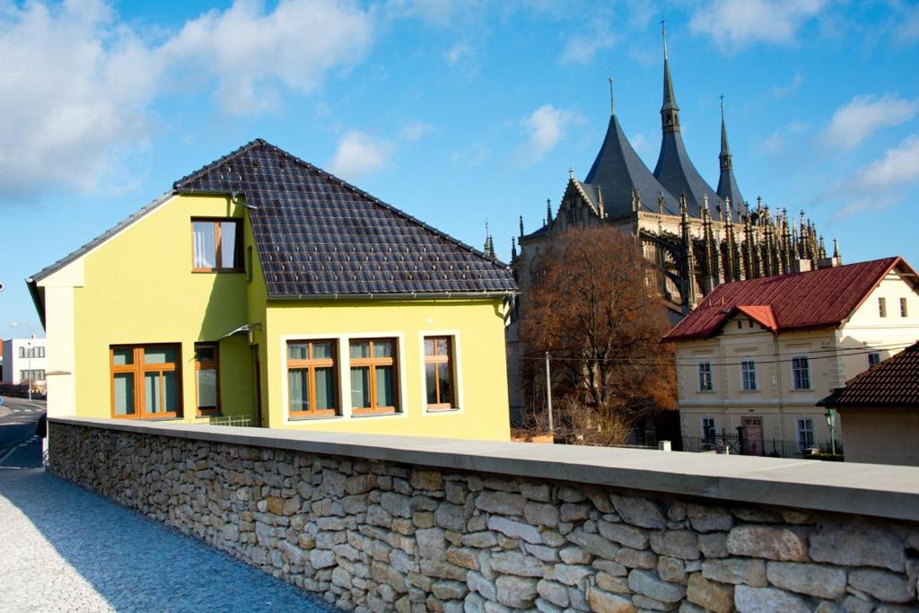 a yellow house on a wall with a castle in the background at Elvíra ubytování v soukromém in Kutná Hora