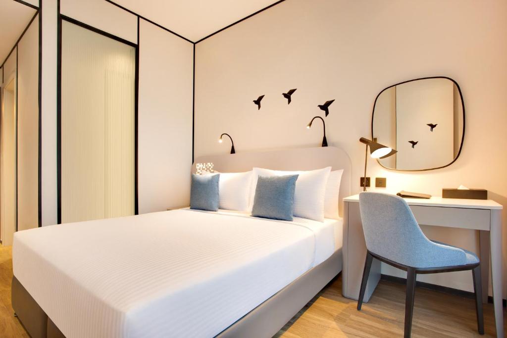 a bedroom with a bed and a desk and a chair at Lemon Tree Hotel, Jumeirah Dubai in Dubai