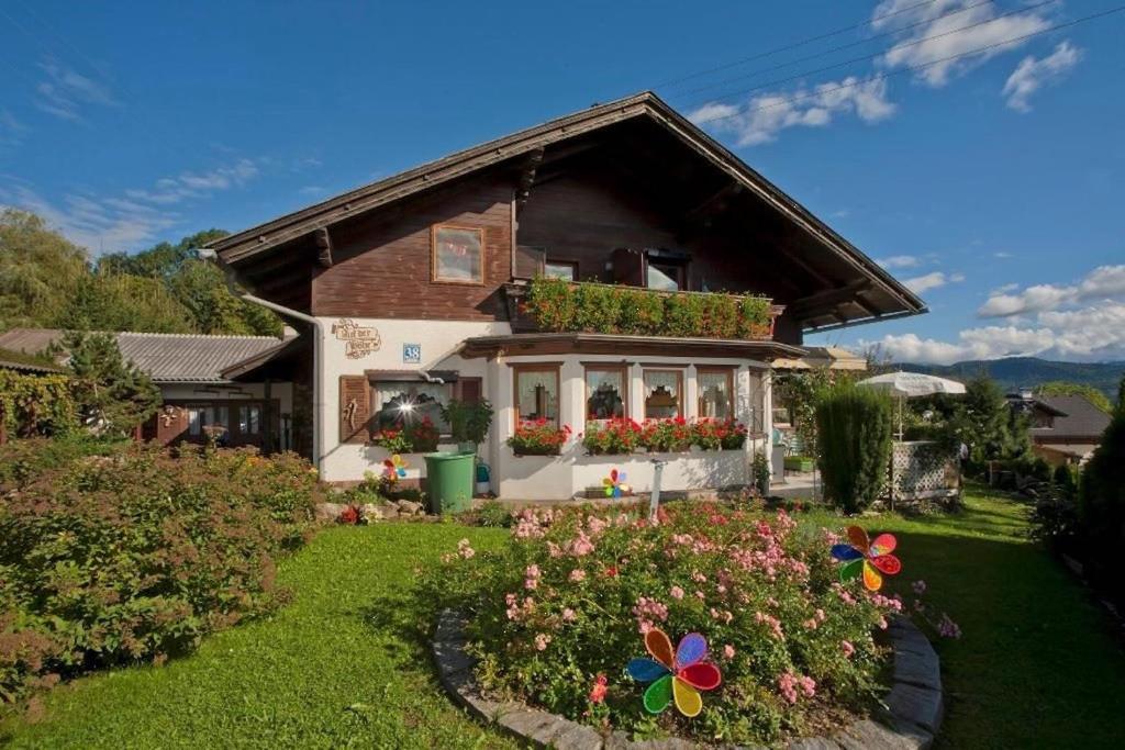 una casa con un giardino fiorito di fronte di Gästehaus auf der Höhe a Keutschach am See