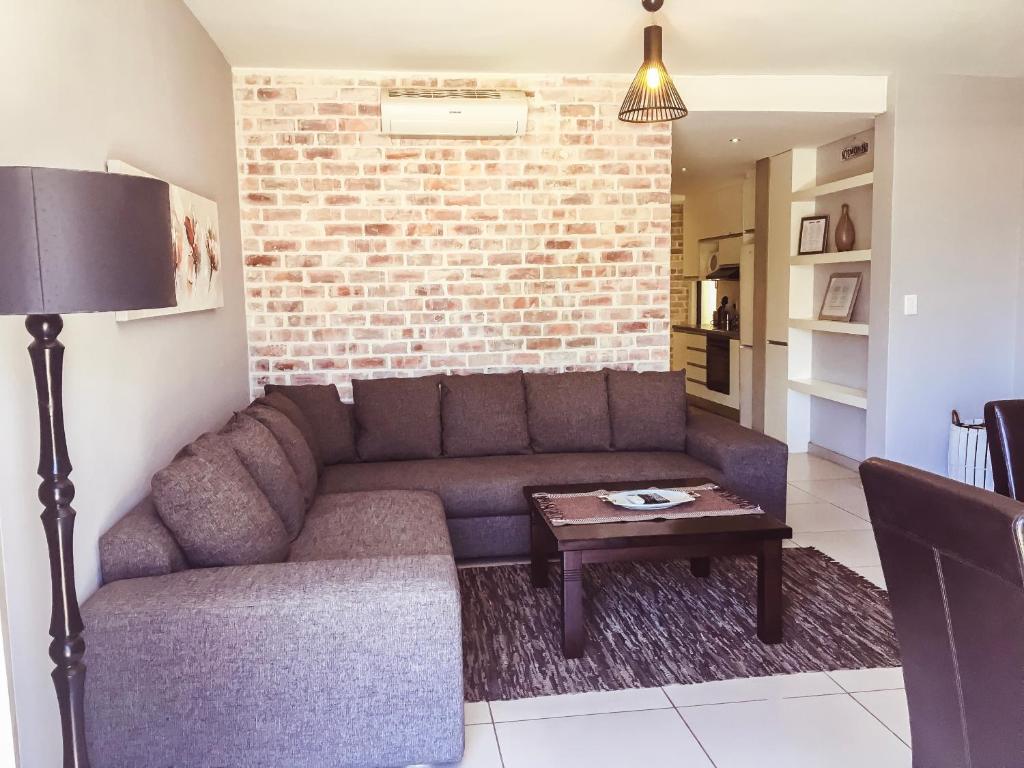 a living room with a couch and a brick wall at Elegant Apartment at Grove Mall in Windhoek