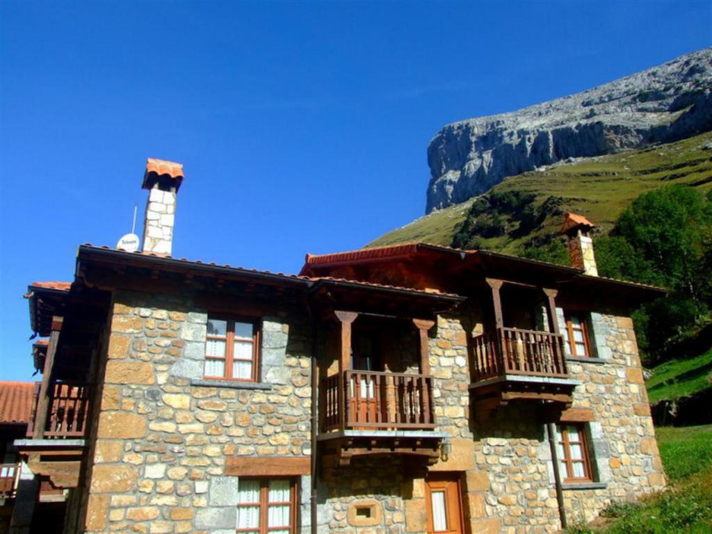 un edificio de piedra con balcón en una montaña en Las Casucas de Ason, en Arredondo