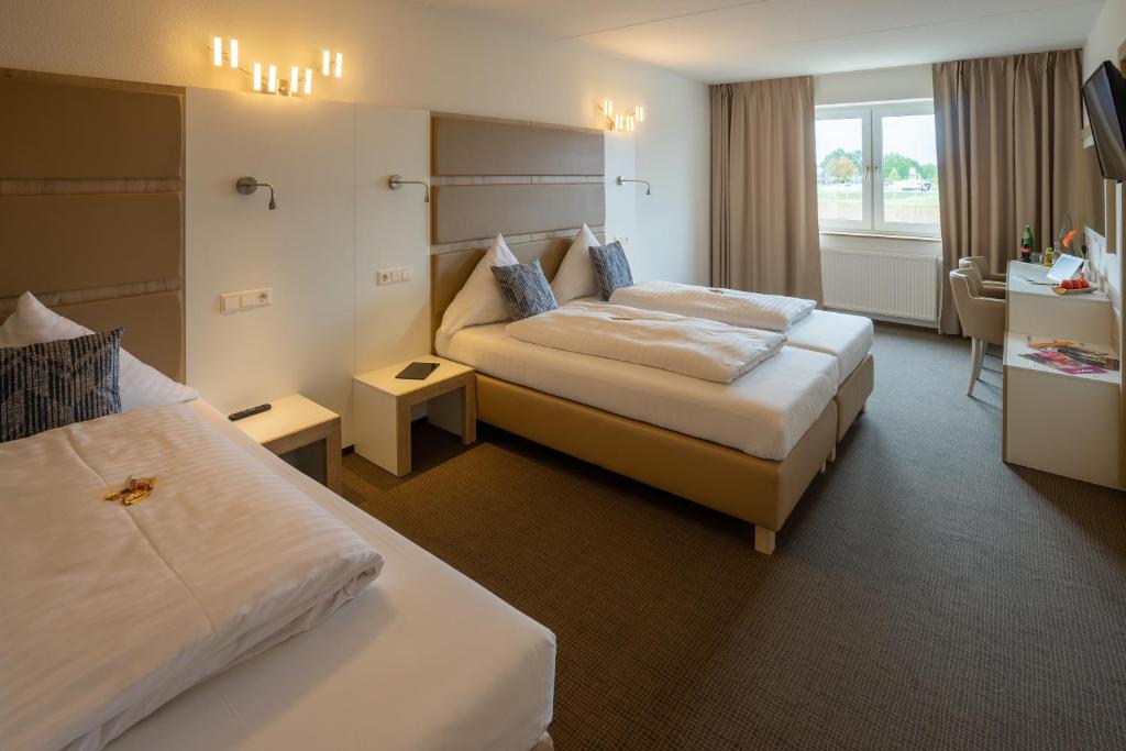 ein Hotelzimmer mit zwei Betten und einem Fernseher in der Unterkunft Confour Hotel in Burgdorf