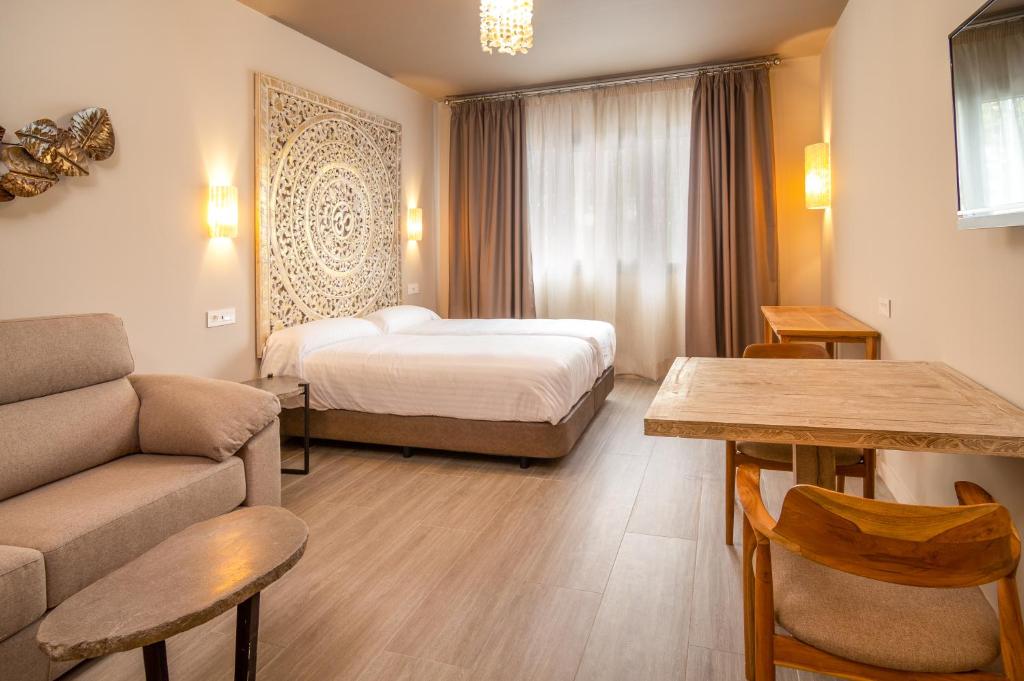 um quarto de hotel com uma cama e um sofá em Apartamentos Sevilla Este by QHotels em Sevilha