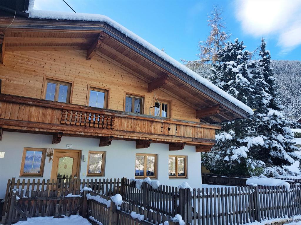 ein Holzhaus mit einem Zaun im Schnee in der Unterkunft Ferienwohnung Point in Hainzenberg