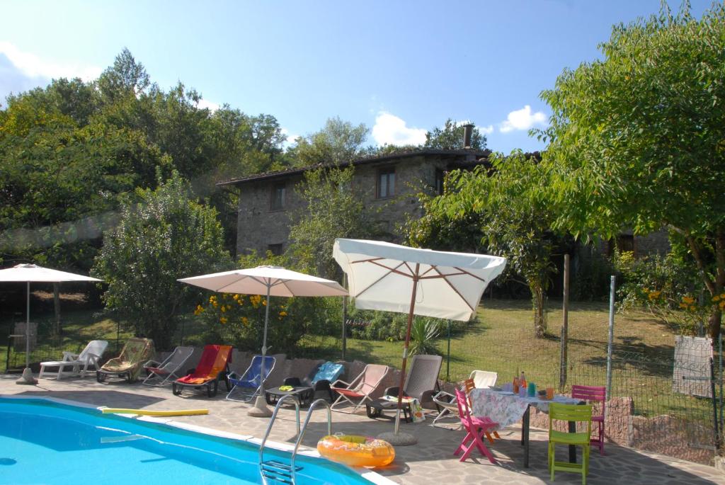 a pool with chairs and umbrellas next to a house at La Capannella in Gallicano