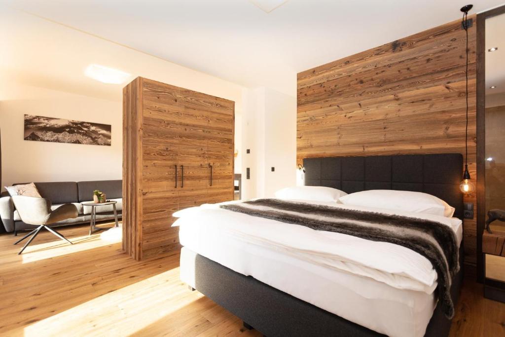 ein Schlafzimmer mit einem großen Bett und einer Holzwand in der Unterkunft Ferienwohnungen HARASSER - ERLEBEN in Fieberbrunn