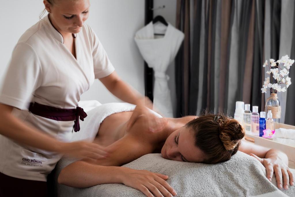 a woman giving a man a massage on a bed at Le Pinarello in Sainte-Lucie de Porto-Vecchio