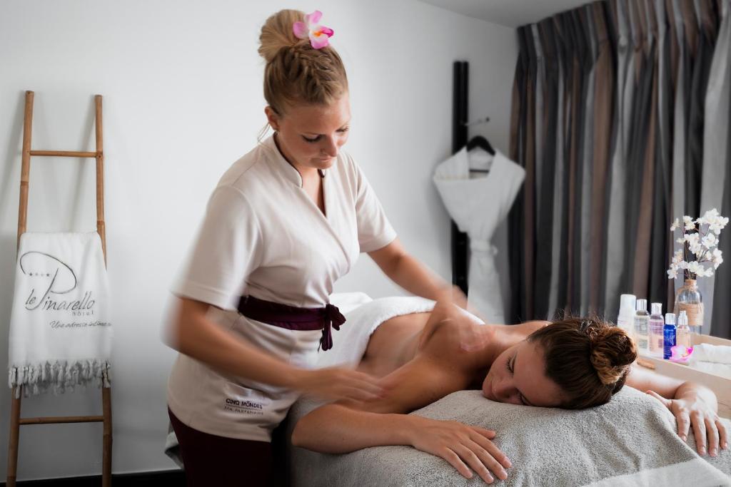 a woman giving a man a massage on a bed at Le Pinarello in Sainte-Lucie de Porto-Vecchio