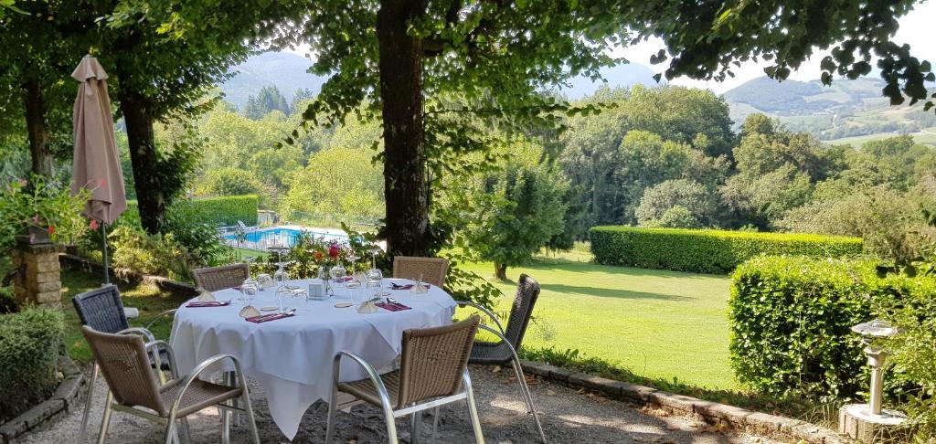 einen Tisch mit einer weißen Tischdecke und Stühlen im Garten in der Unterkunft Hotel Les Mésanges in Saint-Martin-dʼUriage