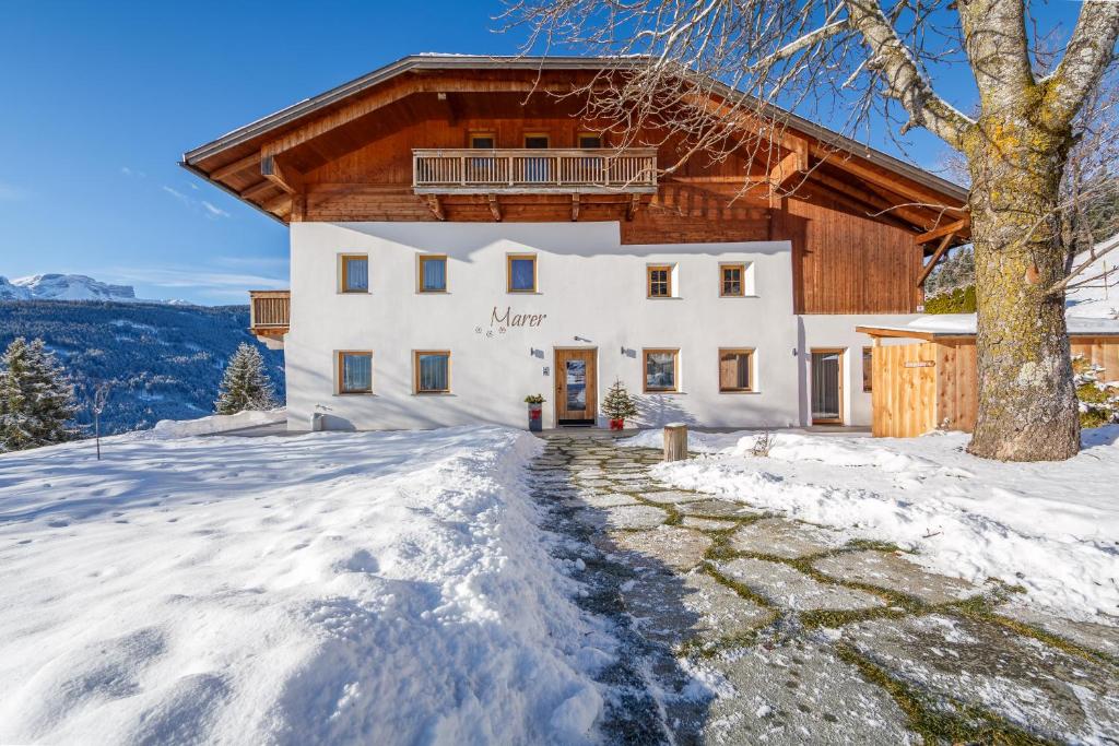 a large white house with a wooden roof at Agriturismo MARER Urlaub auf dem Bauernhof in Villabassa