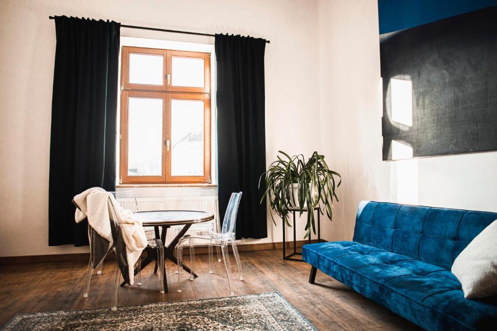 een woonkamer met een blauwe bank en een tafel bij Vilao Apartments in Krakau