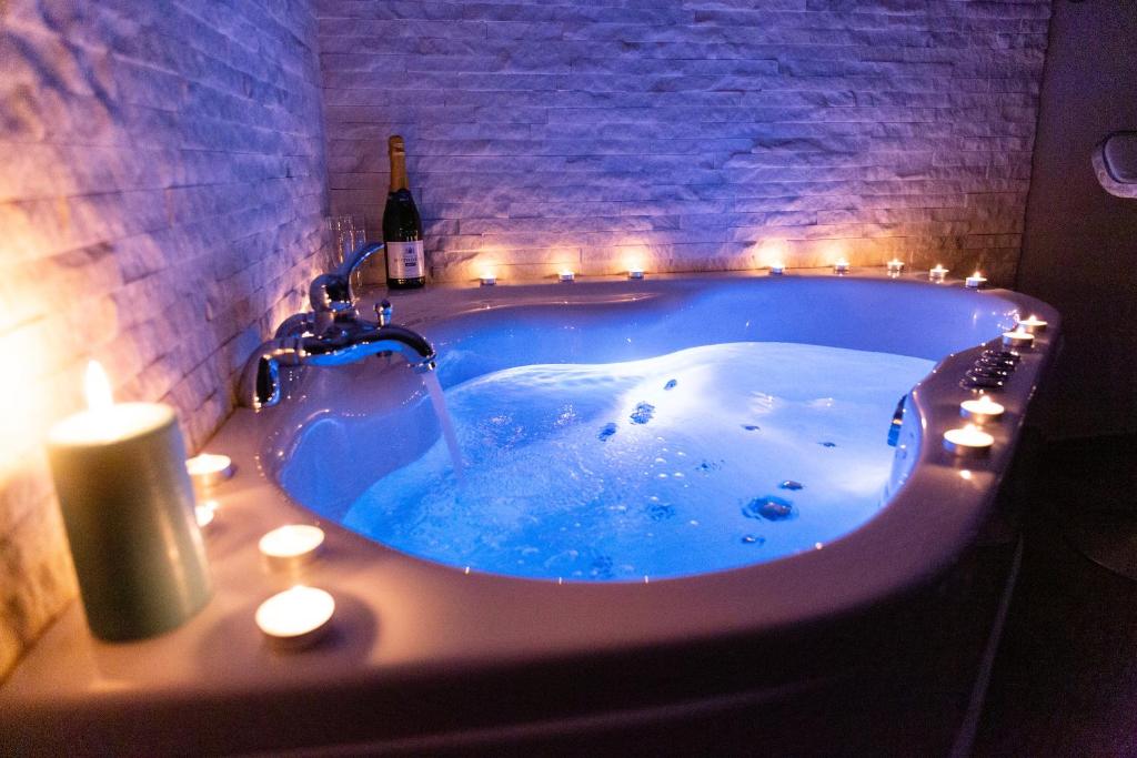 a bathroom with a tub with candles and a bottle of wine at SPA Apartment Nalis in Niš