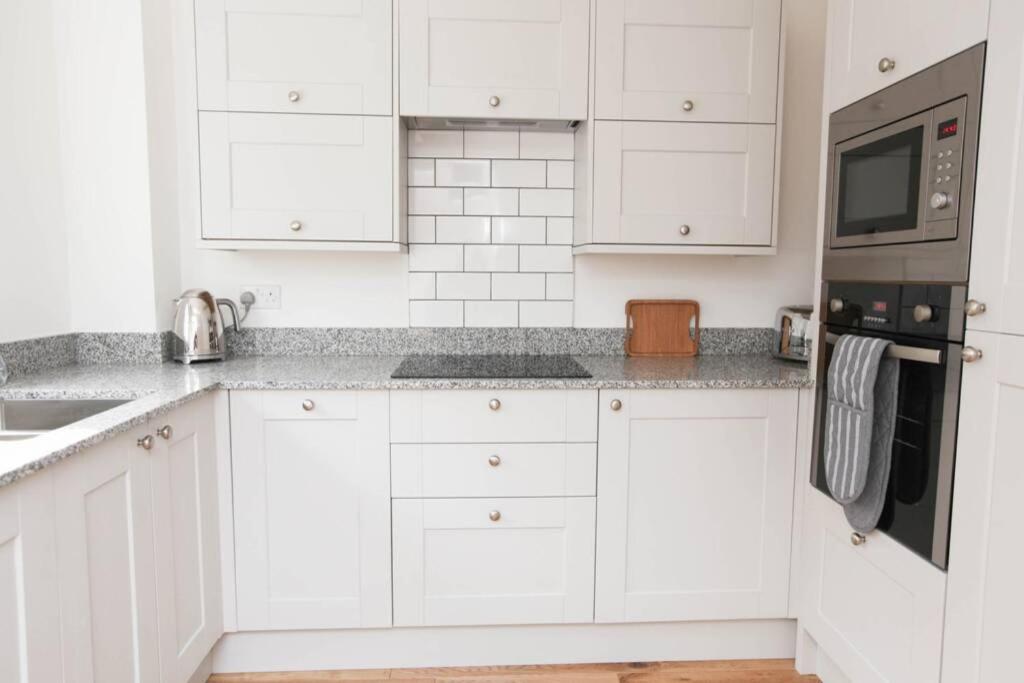 a white kitchen with white cabinets and appliances at Raynolds Cottage Blidworth in Blidworth