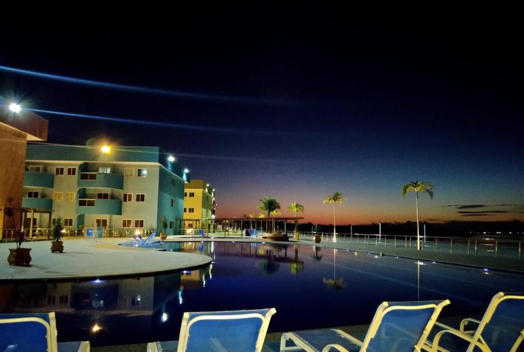 una piscina con sillas frente a un edificio en apart-hotel Golden Lake, en Arraial do Cabo