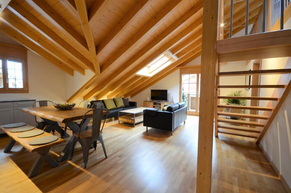 una sala da pranzo e un soggiorno con soffitto in legno. di Waterfall View Luxury Penthouse a Lauterbrunnen