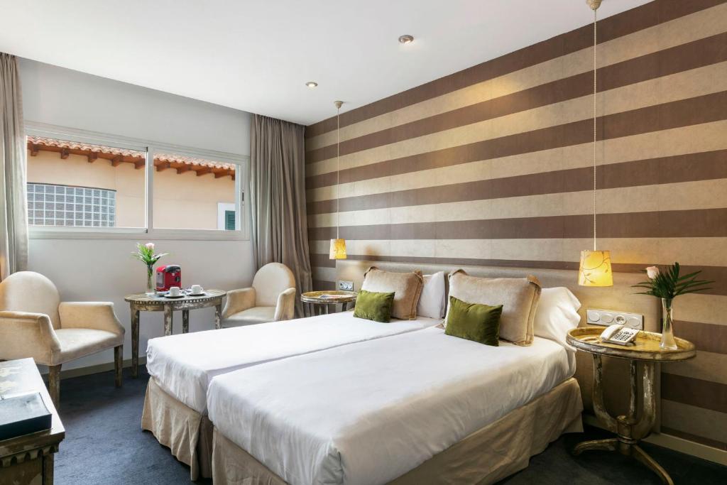 a hotel room with a large bed and chairs at Globales Acis y Galatea in Madrid