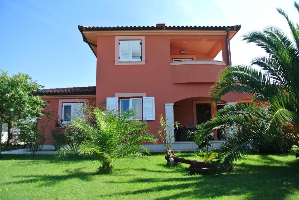 een rood huis met palmbomen ervoor bij VILLA ANCORA MEDULIN in Medulin