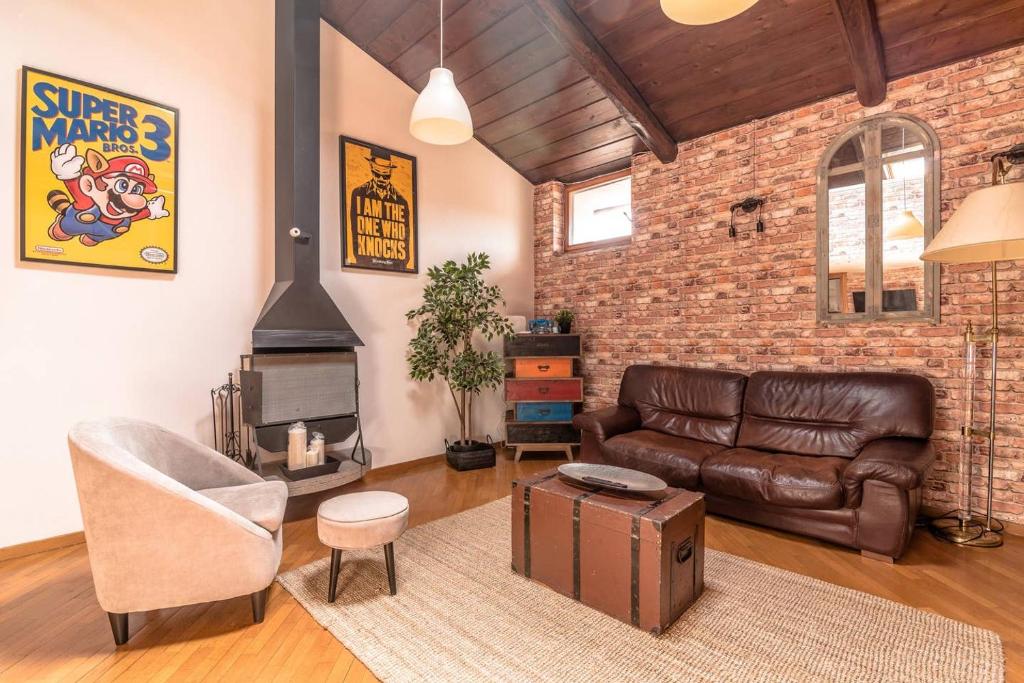 a living room with a leather couch and a brick wall at Loft 60 - EXCLUSIVE LOFT ROME CITY CENTER in Rome