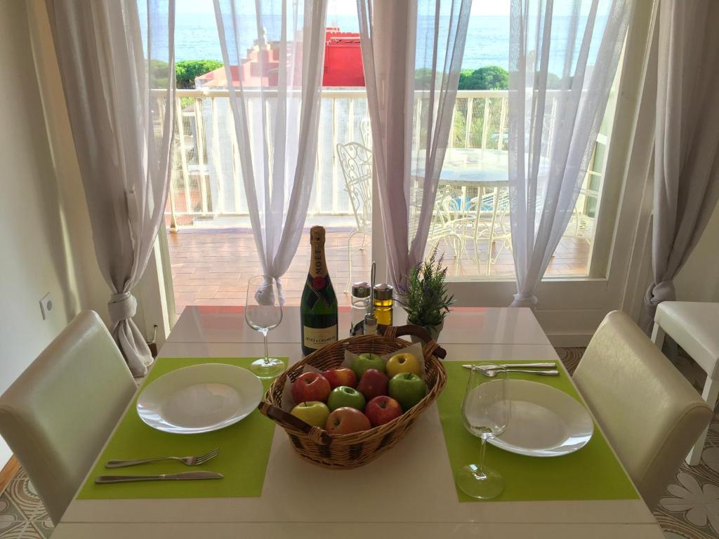 una mesa con una cesta de fruta y una botella de vino en Sunshine apartment with great sea view and terrace in Malgrat de Mar, en Malgrat de Mar